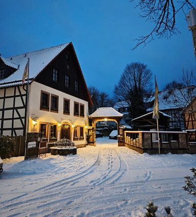 Winterliche Szene eines Fachwerkhauses mit Schnee und Abendbeleuchtung.