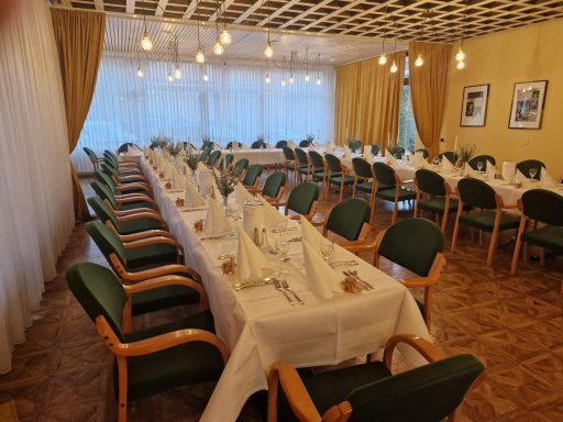 Gedeckter Tisch in einem eleganten Restaurant mit grünen Stühlen und natürlichem Licht.