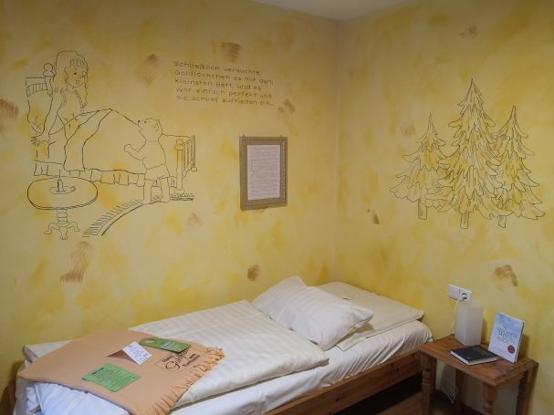 Ein Schlafzimmer mit gelben Wänden, einem Bett und Zeichnungen an der Wand.