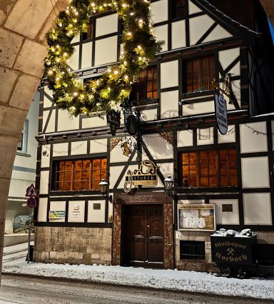 Historisches Fachwerkhaus mit Weihnachtskranz und Schneedecke vor dem Eingang.
