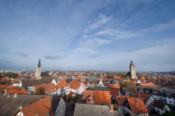Panorama einer Stadt mit roten Dächern und zwei markanten Kirchtürmen.