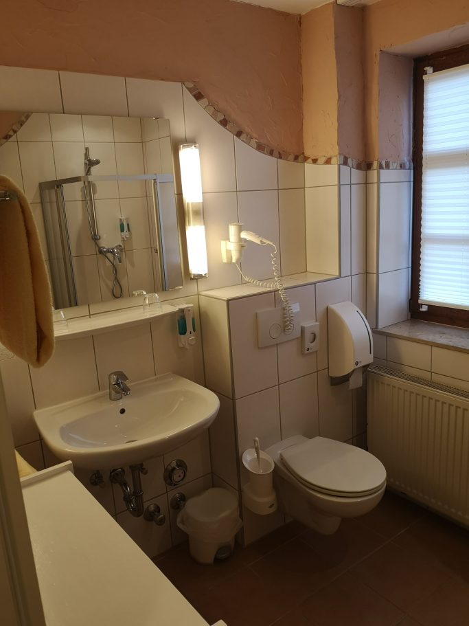 Modernes Badezimmer mit Waschbecken, Toilette und Dusche, warmen Farbton.