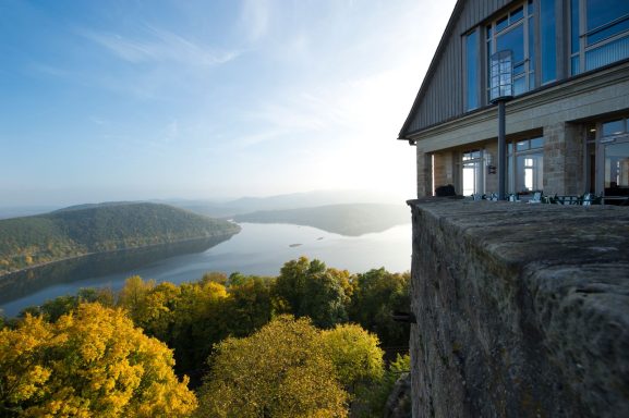 Blick auf einen Fluss umgeben von Bäumen und sanften Hügeln bei Sonnenaufgang.