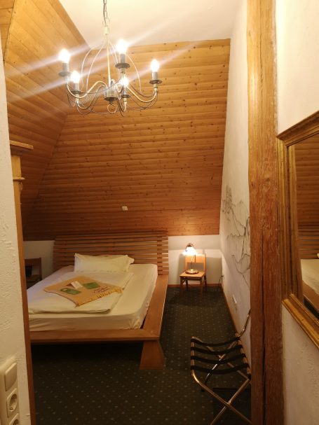 Gemütliches Schlafzimmer mit Holzdecken, Doppelbett, Nachttisch und stilvoller Beleuchtung.