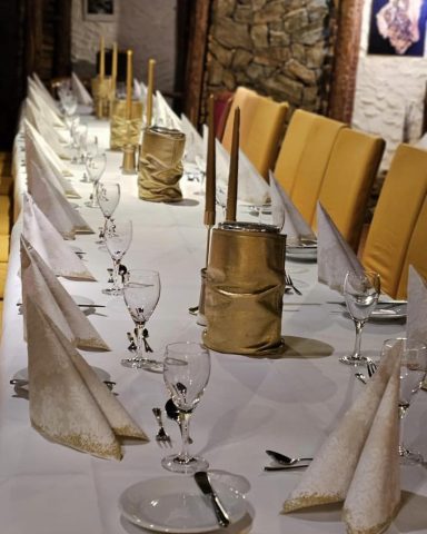 Elegantly gedeckte Tafel mit weißen Tischdecken und goldenen Elementen.