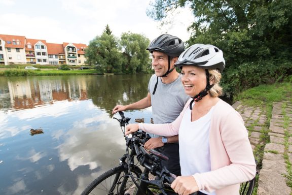Paar mit Fahrrädern steht am Fluss und genießt die Aussicht.