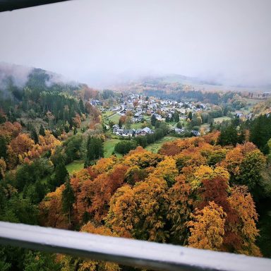 Blick auf ein buntes Herbstpanorama mit einem Dorf in der Ferne.