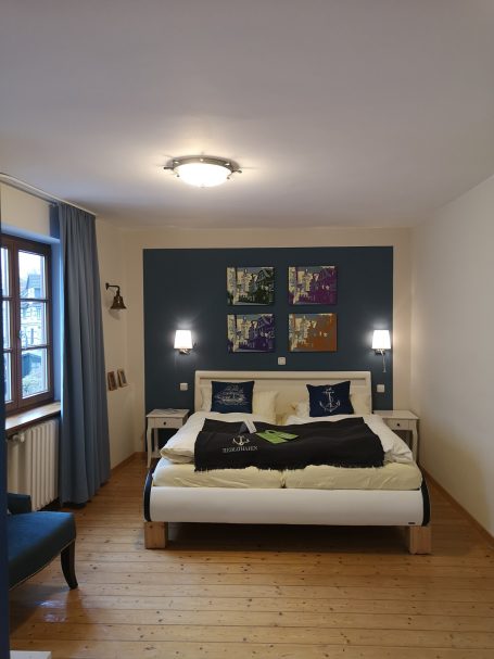 Helles Schlafzimmer mit einem großen Bett, blauer Wand und Holzfußboden.