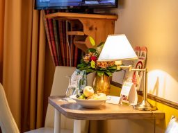 Ein dekorierter Tisch mit Lampe, Blumenstrauß, Wasser und einem Obstteller.