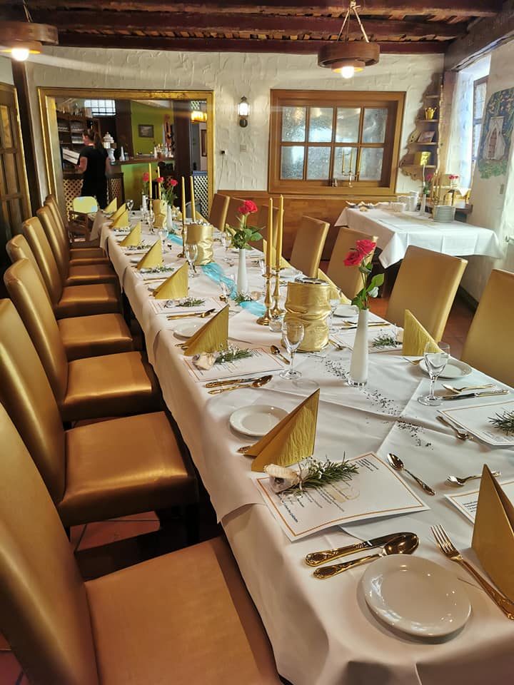 Langer Tisch mit goldenen Stühlen, festlich gedeckt für ein Dinner.