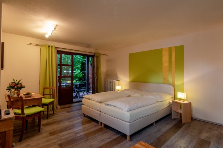 Helles Schlafzimmer mit Doppelbett, Holzboden und Zugang zur Terrasse.