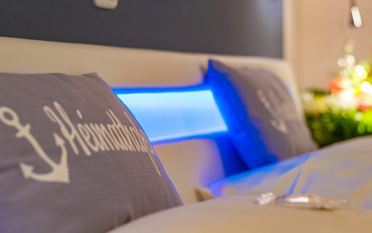 Zwei Kissen mit Anker-Motiv und blauer LED-Beleuchtung im Hintergrund.