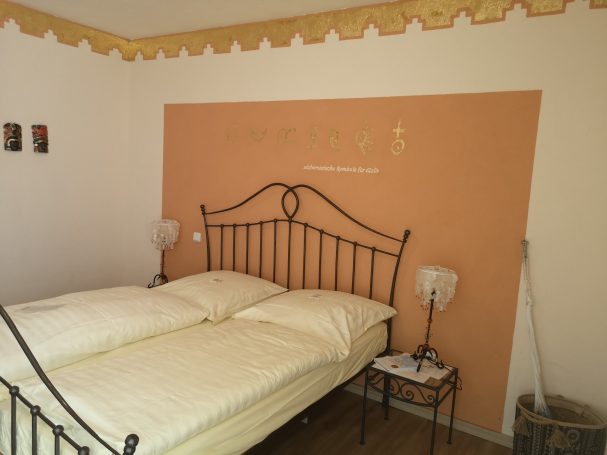 Gemütliches Schlafzimmer mit einem Doppelbett und orangefarbener Wand.