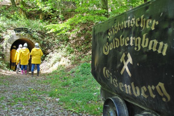 Besucher im Bergwerk mit gelben Regenjacken gehen durch den Tunnel.