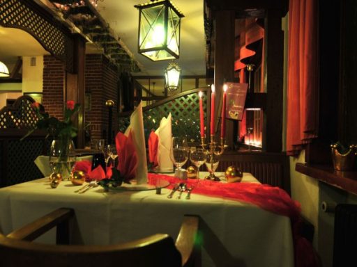 Elegant Tisch gedeckt mit Rosen, Kerzen und roten Dekorationen in einem romantischen Restaurant.