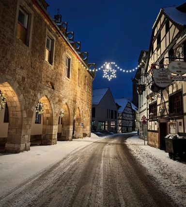 Schneebedeckte Straße in einer festlich beleuchteten Stadt bei Nacht.
