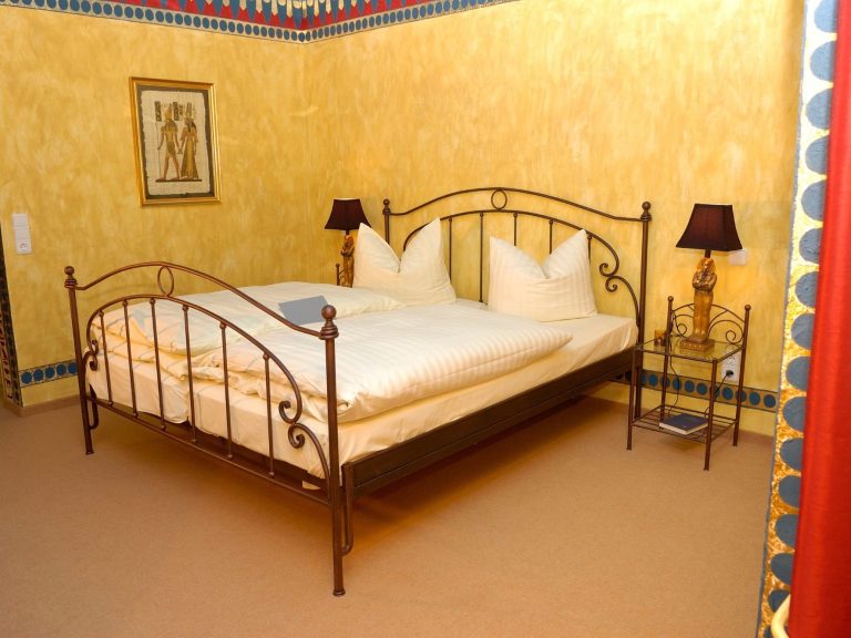 Gemütliches Schlafzimmer mit einem Doppelbett und zwei Nachttischen. Wände in Gelb.