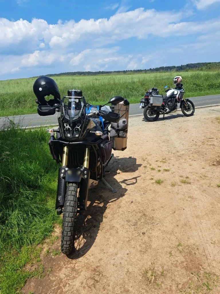 Ein schwarzes Motorrad mit Koffersystem auf einem Feldweg, im Hintergrund ein zweites Motorrad.