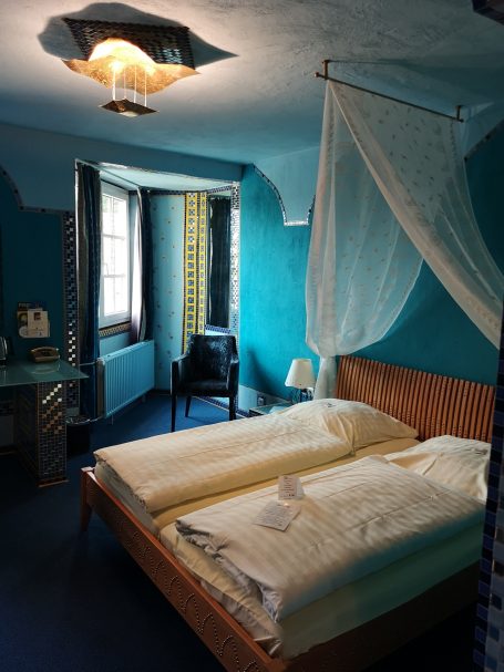 Gemütliches Schlafzimmer mit zwei Betten, blauen Wänden und einem weißen Baldachin.