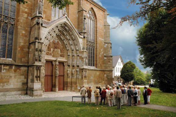 Gruppe von Menschen vor einer historischen Kirche mit gotischer Architektur.